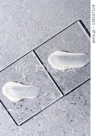 A sample of white body cosmetics on a glass square. Grey background. A sample of white body cosmetics on a glass square. Grey background. 136507329
