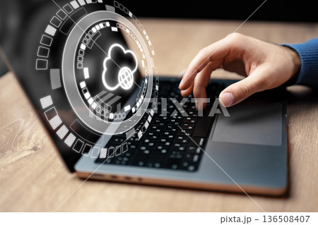 User accesses cloud services on laptop while working at wooden desk 136508407