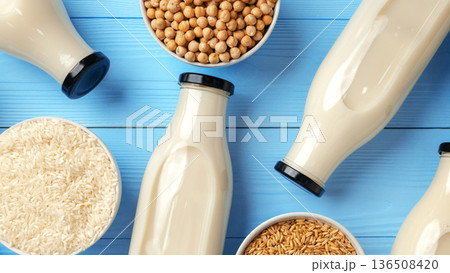 Different types of plant-based milk in glass bottles and bowls on blue background Different types of plant-based milk in glass bottles and bowls on blue background 136508420