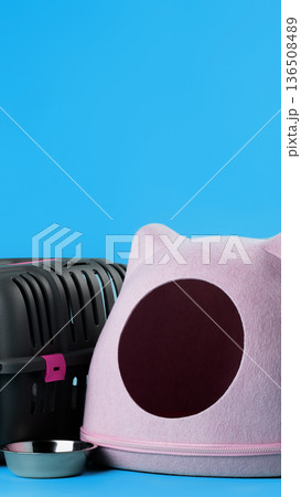 Cat carrier and food bowl on blue background during indoor setup for pet travel Cat carrier and food bowl on blue background during indoor setup for pet travel 136508489