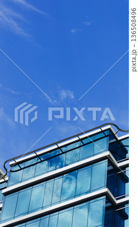 Modern office building with glass windows under a clear blue sky in the city 136508496