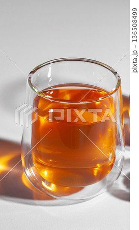 Warm drink in clear glass on simple surface with light shining through Warm drink in clear glass on simple surface with light shining through 136508499