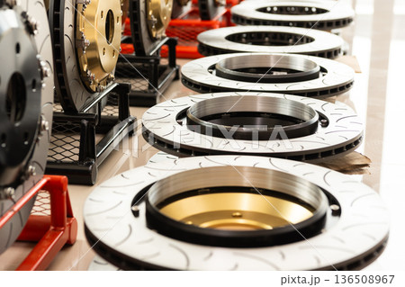 Close up brake disc rotors with drilled and slotted surface performance automotive parts displayed in workshop high quality metal components for vehicle braking system Close up brake disc rotors with drilled and slotted surface performance automotive parts displayed in workshop high quality metal components for vehicle braking system 136508967