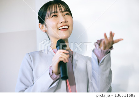 マイクを持って話す若い女性 136511698
