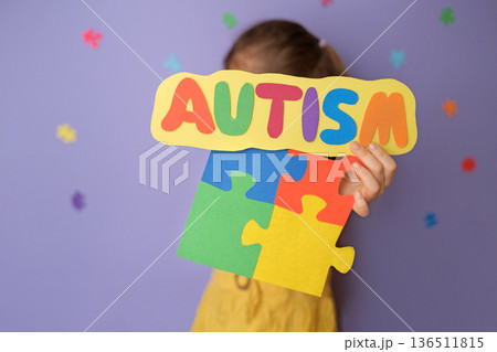 School concept of autism awareness with child holding colorful puzzle pieces and autism sign. Inclusive education, classroom support, neurodiversity acceptance and equal learning opportunities. School concept of autism awareness with child holding colorful puzzle pieces and autism sign. Inclusive education, classroom support, neurodiversity acceptance and equal learning opportunities. 136511815