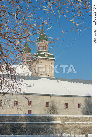 Old monastery towers with green roofs in a sunny winter day with hoarfrost branches 136512457