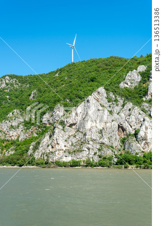Wind turbine on forested mountain above rocky river cliffs Wind turbine on forested mountain above rocky river cliffs 136513386