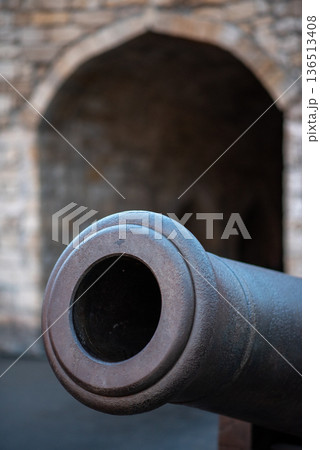 Close-up of antique cannon with stone archway background 136513408
