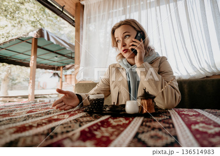 Woman Talking on Phone at a Cafe 136514983
