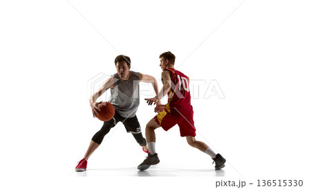 Basketball player changing direction while defender follows on white background. Basketball player changing direction while defender follows on white background. 136515330