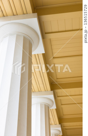 Sunlit columned arcade with tall white pillars Sunlit columned arcade with tall white pillars 136515729