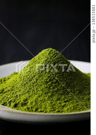 黒い木目背景に映える鮮やかな緑の抹茶の粉末 136515881