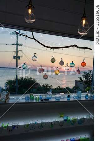 夕暮れの海を望む窓辺に並ぶガラス作品 夕暮れの海を望む窓辺に並ぶガラス作品 136516056