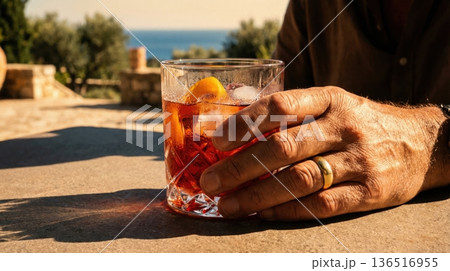 Refreshing Negroni Cocktail Held Over Mediterranean Sea View Refreshing Negroni Cocktail Held Over Mediterranean Sea View 136516955