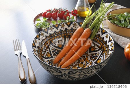 Multicolored ceramic plates and patterned bowl with vegetables and herbs on black background. Food and traditional cuisine. Top view. Multicolored ceramic plates and patterned bowl with vegetables and herbs on black background. Food and traditional cuisine. Top view. 136518496