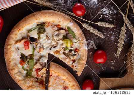 tasty fresh Pizza served at wooden table with cherry tomatos and wheat ears. flat lay. tasty fresh Pizza served at wooden table with cherry tomatos and wheat ears. flat lay. 136518655