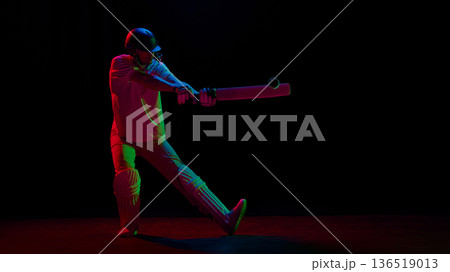 Cricket batsman striking ball mid air in vibrant neon studio. 136519013