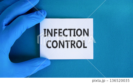 Infection control symbol. Concept words Infection control on beautiful white card. Doctor's hand in blue medical glove. Beautiful blue background. Medical healthy lifestyle infection control concept. Infection control symbol. Concept words Infection control on beautiful white card. Doctor's hand in blue medical glove. Beautiful blue background. Medical healthy lifestyle infection control concept. 136520035