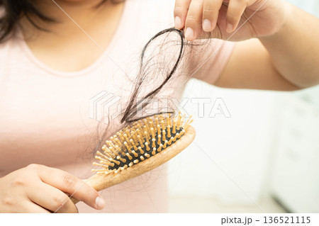 Asian woman have problem with long hair loss attach to comb brush. 136521115