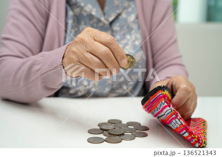 Asian senior or elderly old lady woman holding counting coin money in bag. Poverty, saving problem in retirement. Asian senior or elderly old lady woman holding counting coin money in bag. Poverty, saving problem in retirement. 136521343