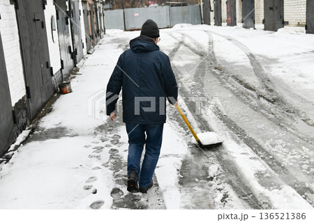 A man shovels snow with a shovel. Cleaning, winter, season, street, work A man shovels snow with a shovel. Cleaning, winter, season, street, work 136521386