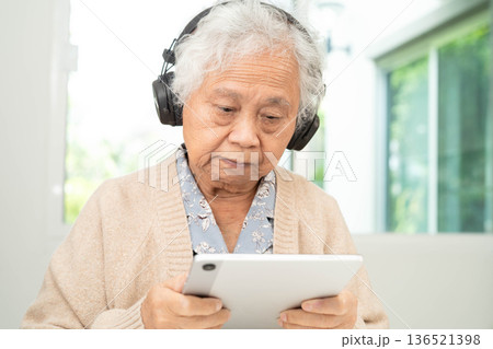 Asian senior woman patient happy to use earphone to listen relax music. 136521398