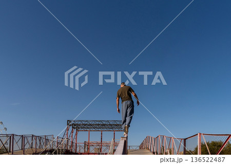 Man walks away balancing on rail in urban parkour zone Man walks away balancing on rail in urban parkour zone 136522487