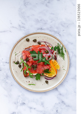 sandwich with freshly smoked salmon, on black bread, with cottage cheese, with herbs and red onions, capers and pieces of citrus fruits, on a marble countertop, breakfast, no people, sandwich with freshly smoked salmon, on black bread, with cottage cheese, with herbs and red onions, capers and pieces of citrus fruits, on a marble countertop, breakfast, no people, 136523066