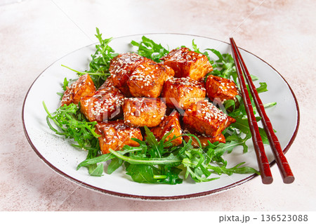 fried salmon slices, teriyaki with sesame seeds, with arugula salad, top view, 136523088