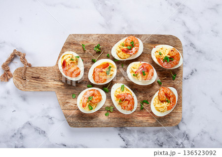 Boiled eggs stuffed with yolk and seasoned with mayonnaise, stuffed eggs with shrimp, on a wooden chopping board, selective focus, close-up, no people, 136523092