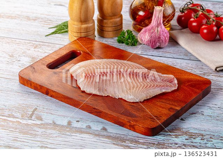 Raw tilapia fish fillet over board Raw tilapia fish fillet over board 136523431