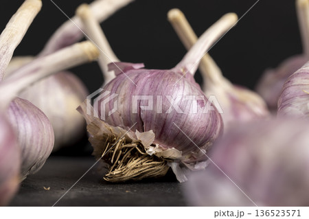 ripe purple garlic on a black table in the kitchen, garlic spices are on a black slate board in the kitchen over cooking ripe purple garlic on a black table in the kitchen, garlic spices are on a black slate board in the kitchen over cooking 136523571