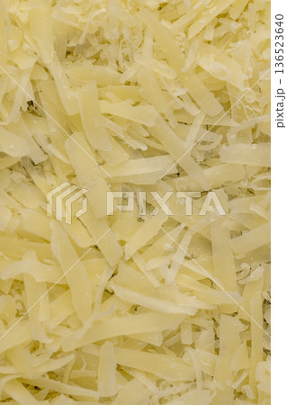 hard ripe cheese grated into small pieces for cooking pasta or pizza, grated piece of yellow cheese as an ingredient for a large dish hard ripe cheese grated into small pieces for cooking pasta or pizza, grated piece of yellow cheese as an ingredient for a large dish 136523640