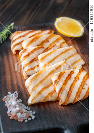 Grilled squid steaks with rosemary and lemon on dark wooden cutting board Grilled squid steaks with rosemary and lemon on dark wooden cutting board 136523916