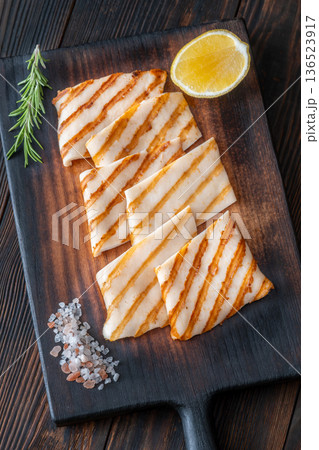 Grilled squid steaks with rosemary and lemon on dark wooden cutting board 136523917