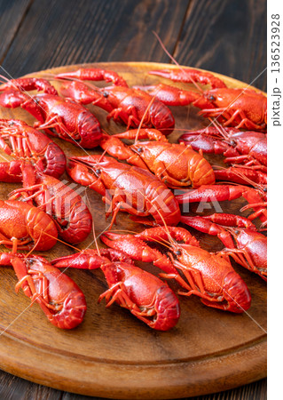Boiled crawfish arranged on wooden board with lemon wedges, rustic background Boiled crawfish arranged on wooden board with lemon wedges, rustic background 136523928