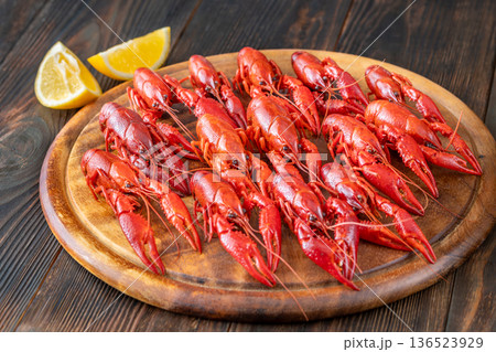 Boiled crawfish arranged on wooden board with lemon wedges, rustic background Boiled crawfish arranged on wooden board with lemon wedges, rustic background 136523929