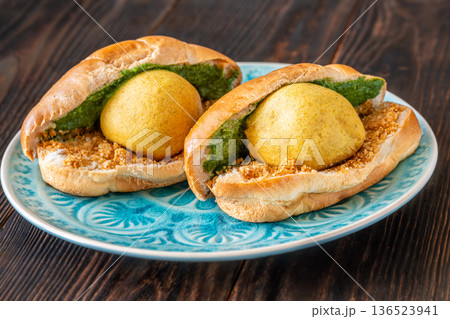 Authentic Vada Pav Indian street food with spicy chutney on rustic wooden background 136523941