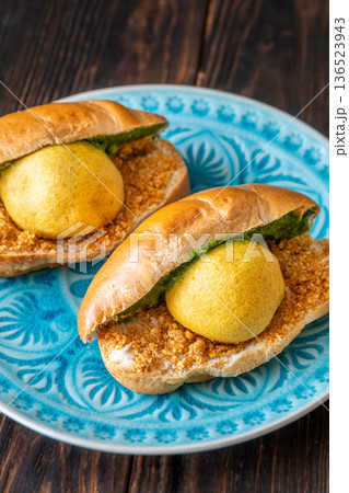 Authentic Vada Pav Indian street food with spicy chutney on rustic wooden background 136523943