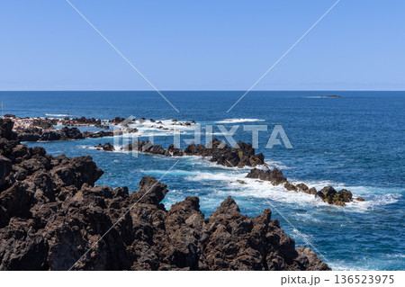 Sunny day Porto Moniz, Madeira Portugal, swimmers enjoy natural volcanic pools beside Atlantic surf 136523975