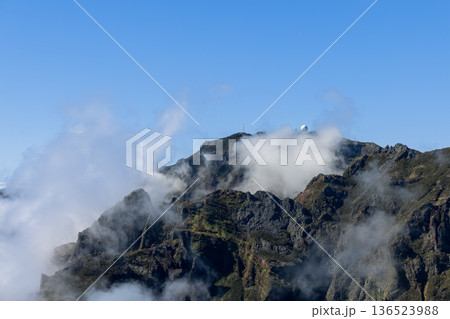 Radar dome on Pico do Arieiro, Madeira, as mist curls around rock towers and sunlit clouds drift 136523988