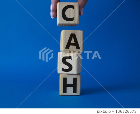 Cash symbol. Concept word Cash on wooden cubes. Beautiful blue background. Businessman hand. Business and Cash concept. Copy space. 136526375
