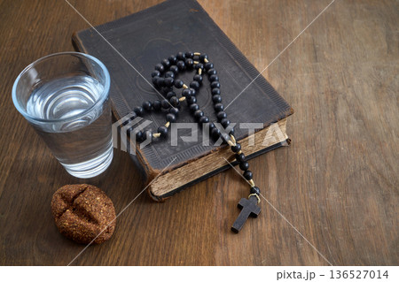 Bible, rosary, water, bread symbolizing lenten fasting and prayer 136527014