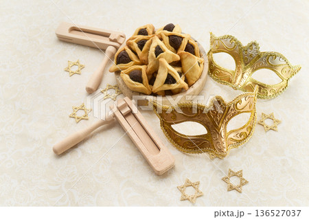 Purim celebration with hamantaschen, graggers, and golden masks 136527037