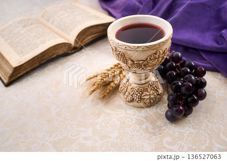 Chalice with wine, grapes, wheat, and bible for communion Chalice with wine, grapes, wheat, and bible for communion 136527063