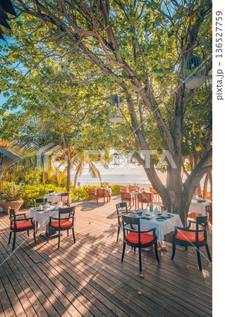 Beach resort outdoors restaurant tables chairs sunset luxury relaxing vibes Beach resort outdoors restaurant tables chairs sunset luxury relaxing vibes 136527759