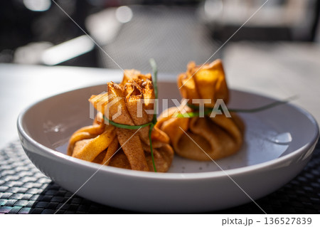 Side view of stuffed crepe bags on white plate Side view of stuffed crepe bags on white plate 136527839