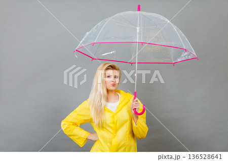 Happy woman wearing raincoat holding transparent umbrella Happy woman wearing raincoat holding transparent umbrella 136528641