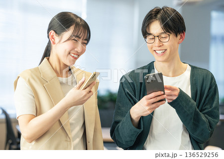 オフィスでスマホを使う男女 136529256