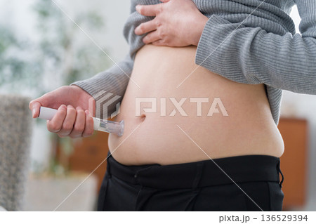 ダイエット注射薬をお腹に打つ女性(自己注射) ダイエット注射薬をお腹に打つ女性(自己注射) 136529394